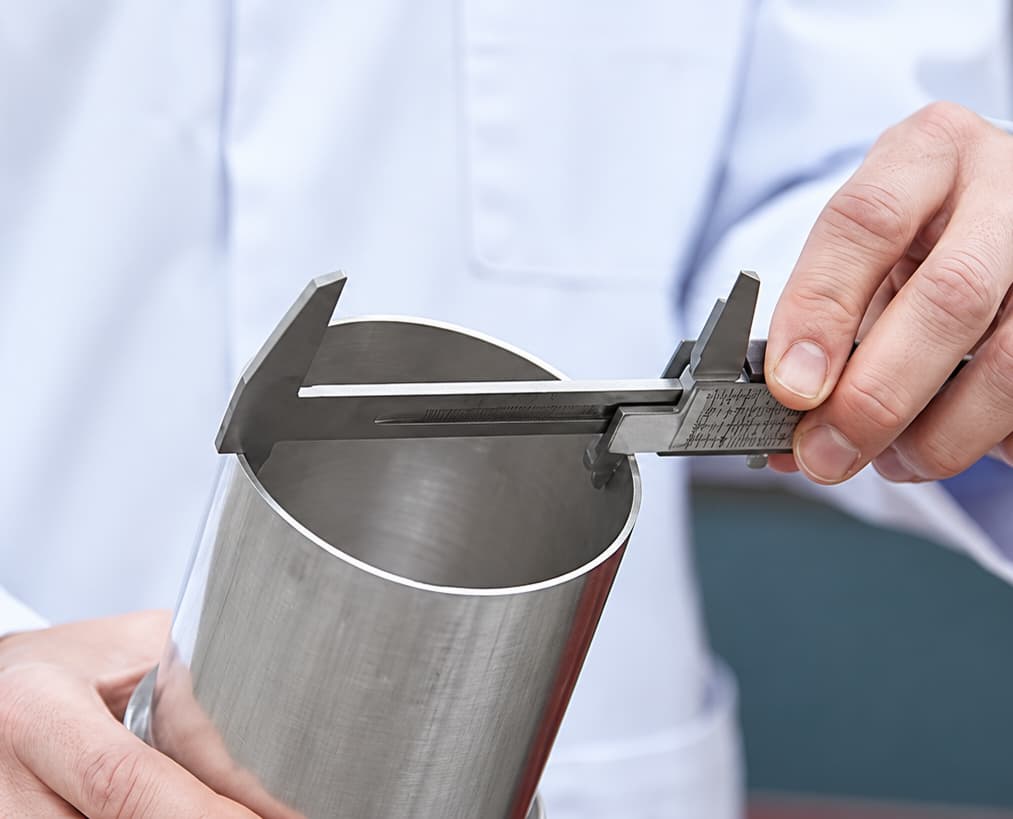 person-measuring-metal-cylinder-with-precision-caliper